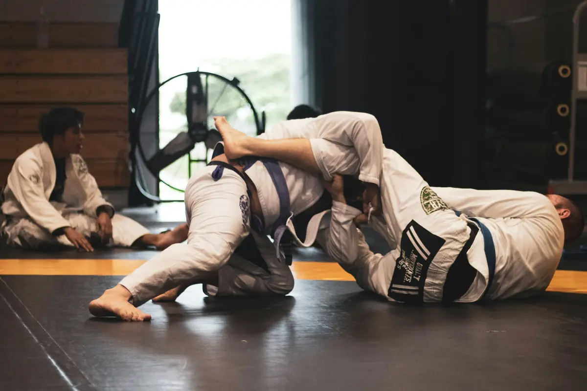 Two people grappling in white gis on the mat