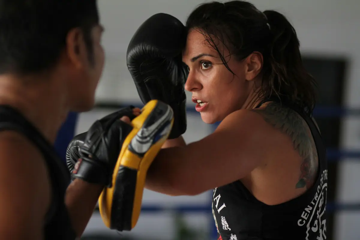 A boxer throwing a punch at a coach's pads
