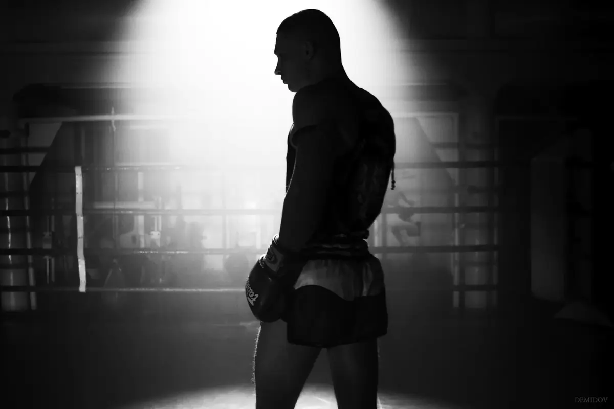 A fighter in shorts and gloves, lit from behind