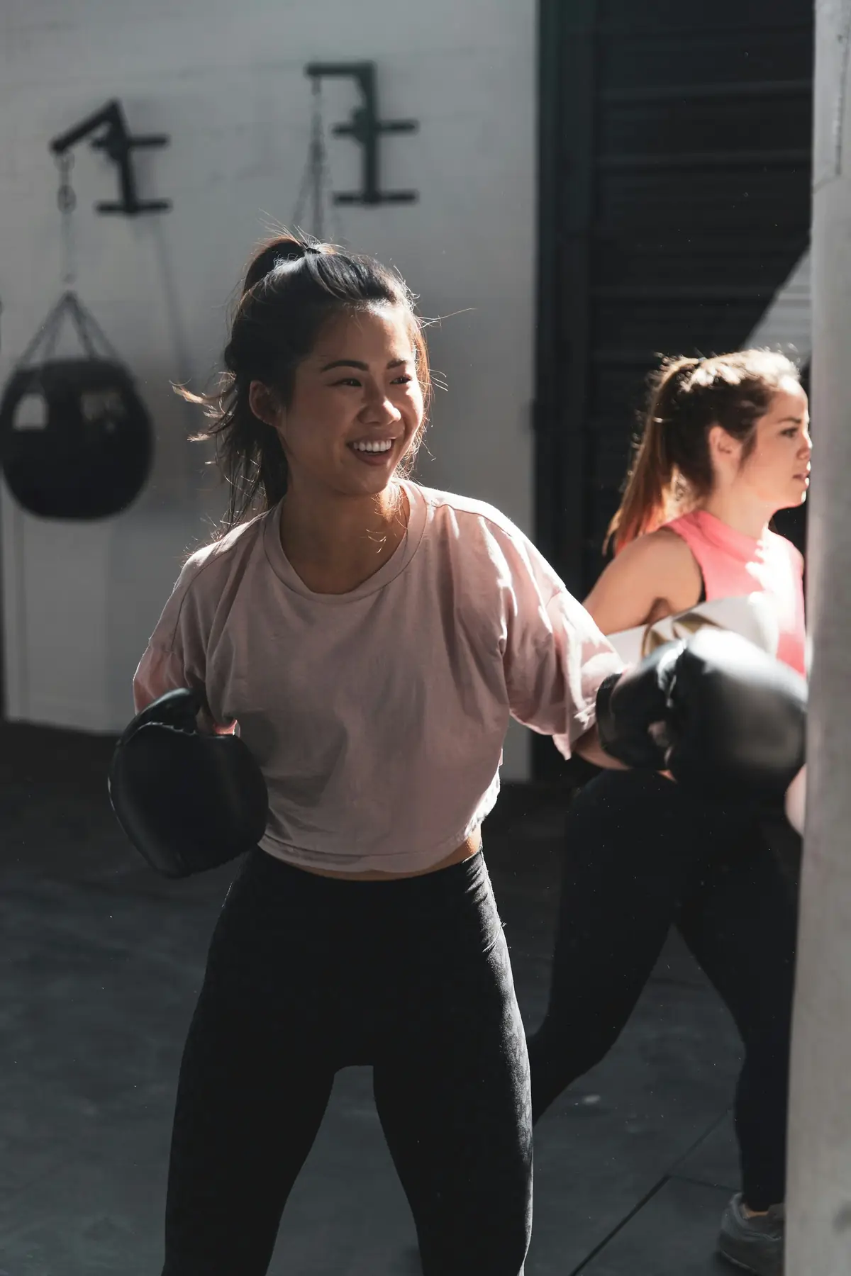 A woman laughing between rounds in boxing gloves